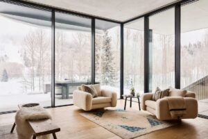 Roh obývacího pokoje s čalouněnými křesly a výhledem na les.