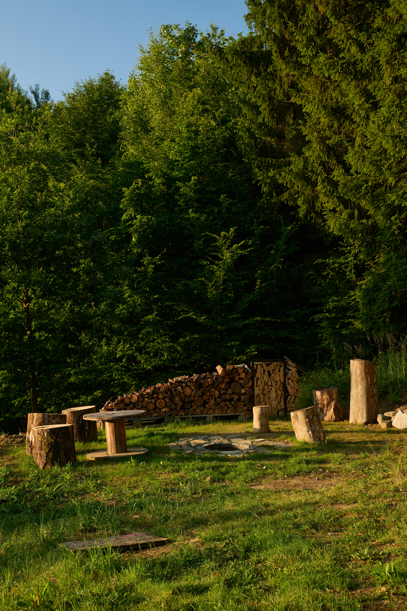 Jednoduché posezení z pařezů a dřevěných špalků u ohniště vytváří přirozené centrum dění u chaty Bebech.