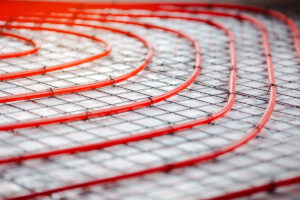 Detail instalace podlahového topení s červenými trubkami uloženými do izolační vrstvy.