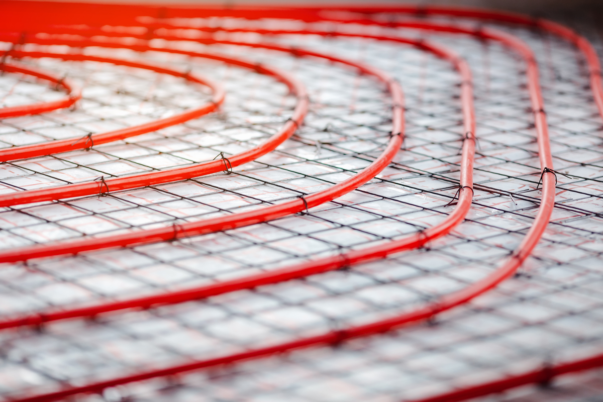 Detail instalace podlahového topení s červenými trubkami uloženými do izolační vrstvy.