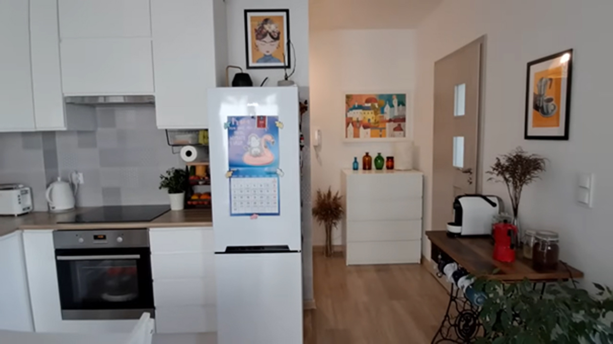 Výhled z kuchyně do předsíně s bílou komodou, barevnými vázami a moderními doplňky.