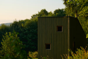 Tmavozelená chata z přírodních materiálů se stala součástí valašského svahu. Její tvar i barva reagují na okolní přírodu.