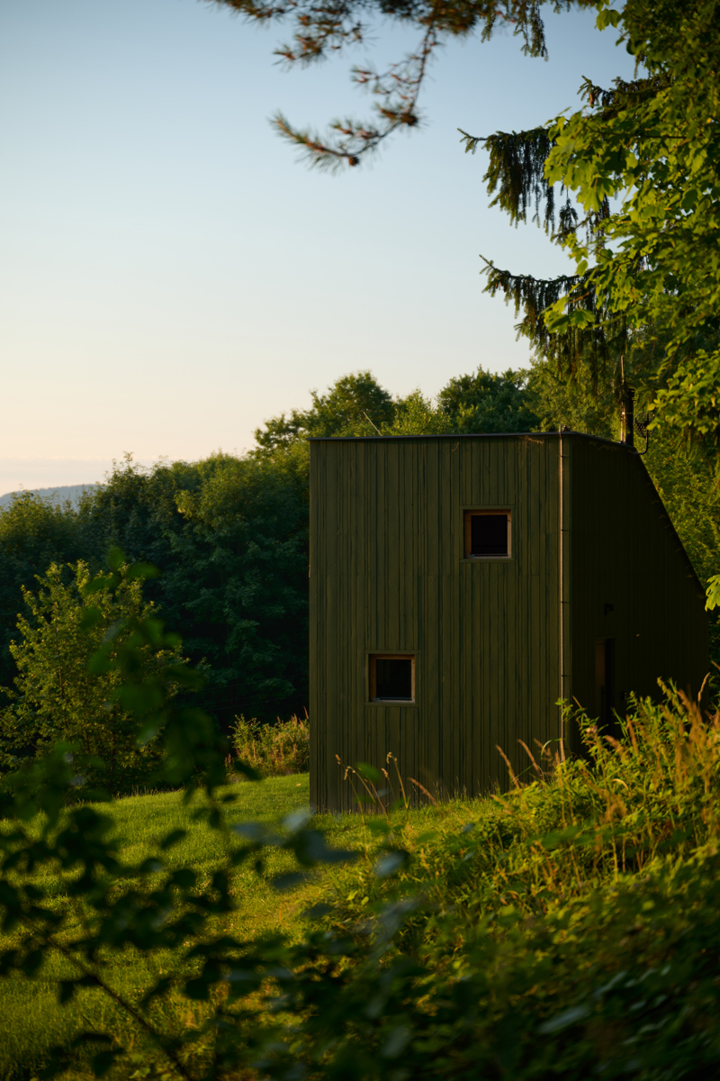 Tmavozelená chata z přírodních materiálů se stala součástí valašského svahu. Její tvar i barva reagují na okolní přírodu.
