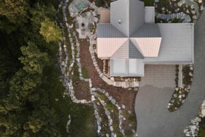 Letecký pohled na dům La Croix odhaluje křížový půdorys i terasovité kaskády zahrady sledující svah