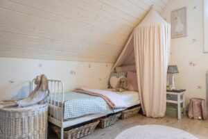 Dětská postel s růžovým baldachýnem a měkkými dekoracemi.