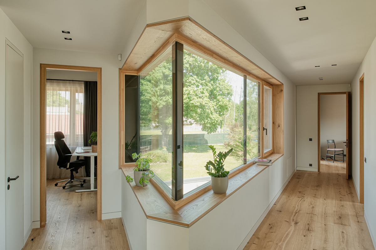Interiér domu s pracovnou a rohovým oknem v chodbičce, lemovaným dřevěným ostěním.