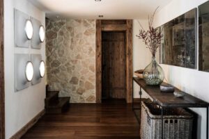 Chodba v Chalet 1936 s přírodní kamennou stěnou, recyklovaným dřevem a vintage dekoracemi v duchu recyklace.