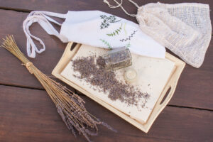 Domácí látkový pytlík s vyšitým dekorem a levandulí rozptýlenou na dřevěném podnose.