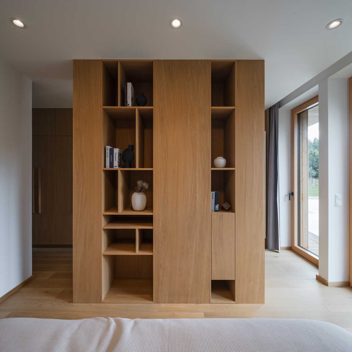 Vestavěný dubový regál s otevřenými nikami v klidném interiéru