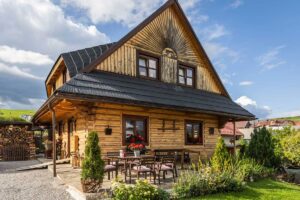 Exteriér dřevěné roubenky s bohatou zahradou, terasou a tradičními prvky, které odrážejí poctivou práci majitelů.