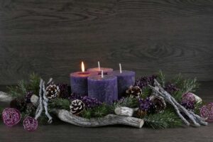 Rustikální adventní věnec s fialovými svíčkami, šiškami, jehličím a dekorativními větvičkami působí teple a přírodně.
