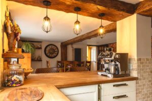 Bílá kuchyňská linka s dřevěnou deskou, závěsnými hrnky a praktickými doplňky ukazuje propojení funkce a teplého domácího designu.