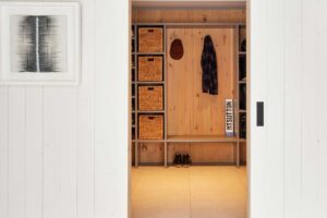 Otevřená šatna ze světlého dřeva ukazuje, jak rekonstrukce proměnila původně tmavé prostory v přehledné a příjemné zázemí pro každodenní život.