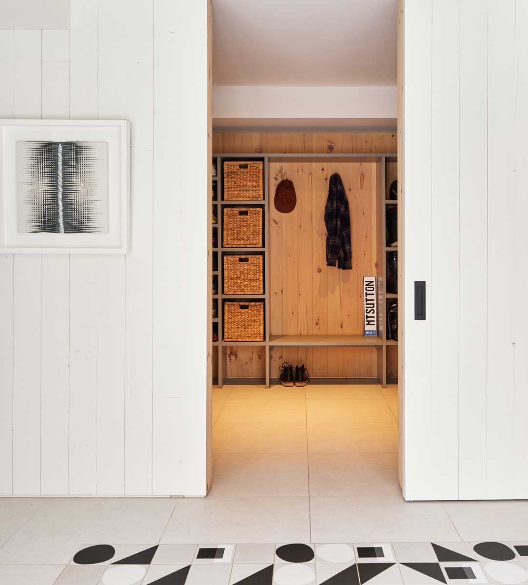 Otevřená šatna ze světlého dřeva ukazuje, jak rekonstrukce proměnila původně tmavé prostory v přehledné a příjemné zázemí pro každodenní život.