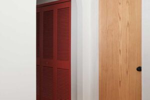 Barevný akcent v podobě červených dveří dodává chodbě hravost a ukazuje, jak může i praktická část domu působit stylově a moderně.