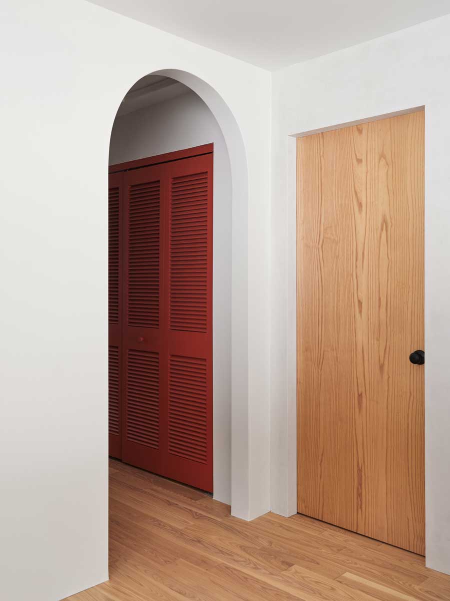 Barevný akcent v podobě červených dveří dodává chodbě hravost a ukazuje, jak může i praktická část domu působit stylově a moderně.