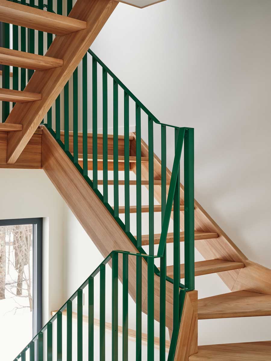 Nové jasanové schodiště se zeleným zábradlím propojuje jednotlivé úrovně domu s lehkostí a stalo se jedním z nejoblíbenějších prvků celé rekonstrukce.