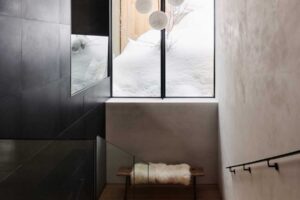 Minimalistické schodiště osvětlené velkým oknem a kulovými závěsnými svítidly.