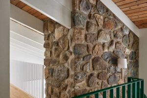 Kombinace původní kamenné stěny a nových dřevěných prvků krásně vystihuje propojení tradice a moderního stylu, které rekonstrukce přinesla.