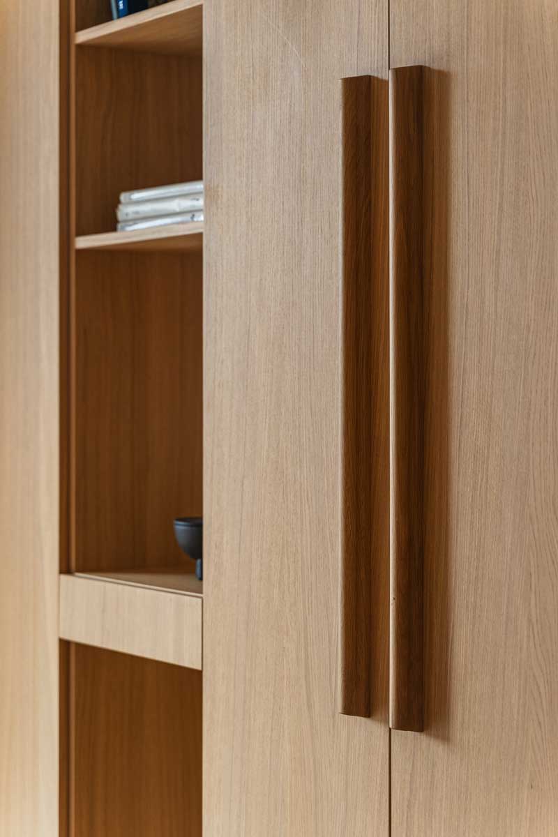 Vestavěná dubová skříň s minimalistickými úchyty v klidném interiéru rodinného domu
