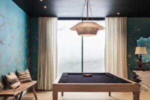 Designová herna s kulečníkovým stolem a jemnou květinovou tapetou.