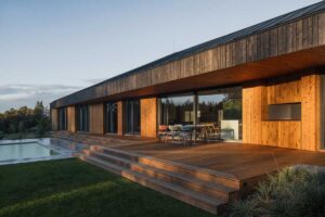 Dřevěná terasa s bazénem u moderního domu zasazeného do krajiny Vysočiny