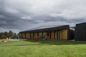 Travnatá zahrada s nízkým rodinným domem zasazeným do svažitého terénu