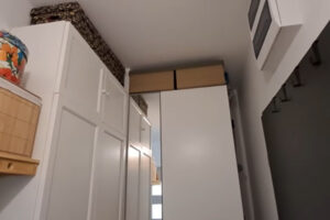 Předsíň s vysokými bílými skříněmi a krabicemi na sezónní věci.