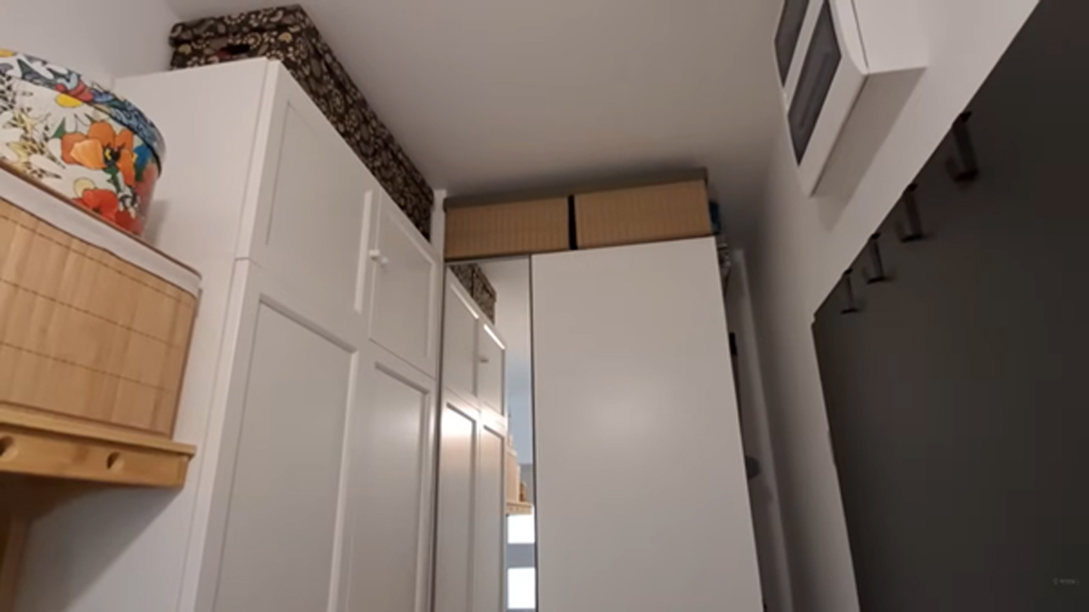 Předsíň s vysokými bílými skříněmi a krabicemi na sezónní věci.