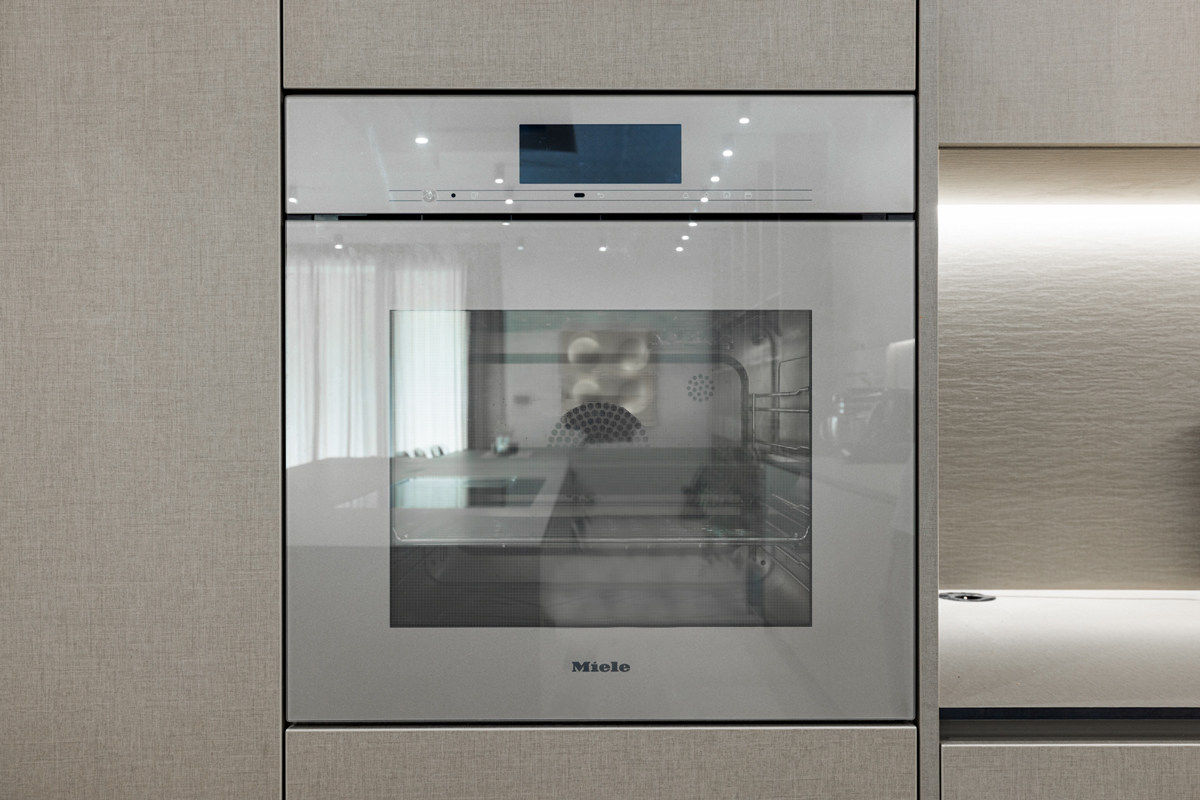 Vestavěná trouba Miele zasazená do kuchyňské linky v šedém dekoru.
