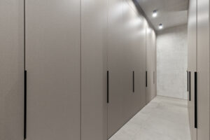 Vestavěné šatní skříně s decentními černými úchyty v úzké chodbě bytu.