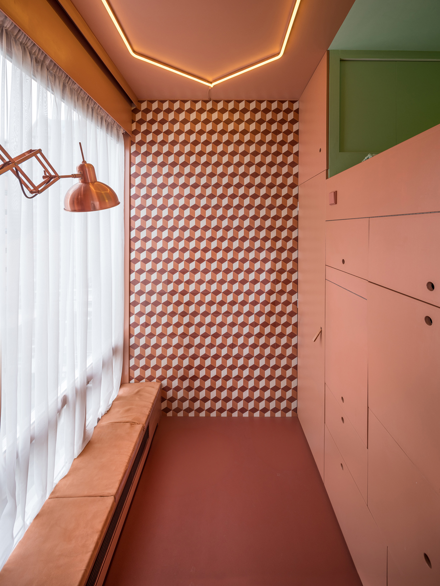 Interiér mikrobytu s oranžovými stěnami, velkým oknem a geometrickým obkladem.