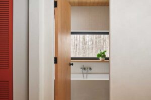 Průchod do koupelny odhaluje kombinaci nadčasových materiálů a jemných barevných akcentů, které oživují původní chatu.