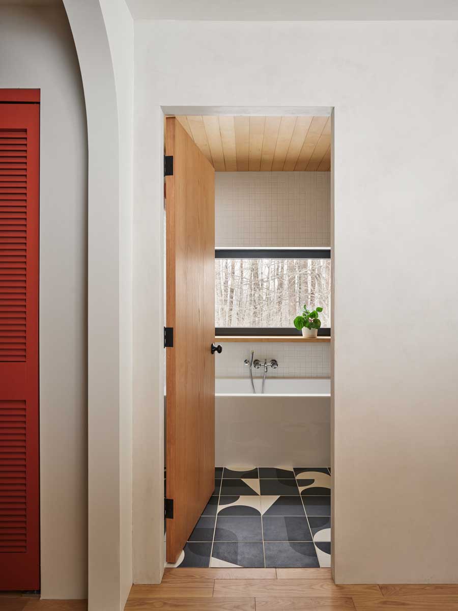 Průchod do koupelny odhaluje kombinaci nadčasových materiálů a jemných barevných akcentů, které oživují původní chatu.