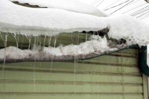 Zamrzlé okapy se sněhem a ledem – ukázka zanedbané zimní údržby, která může poškodit střechu.