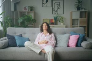 Ženina relaxace v útulném obývacím pokoji, který působí obydleně, barevně a přirozeně.