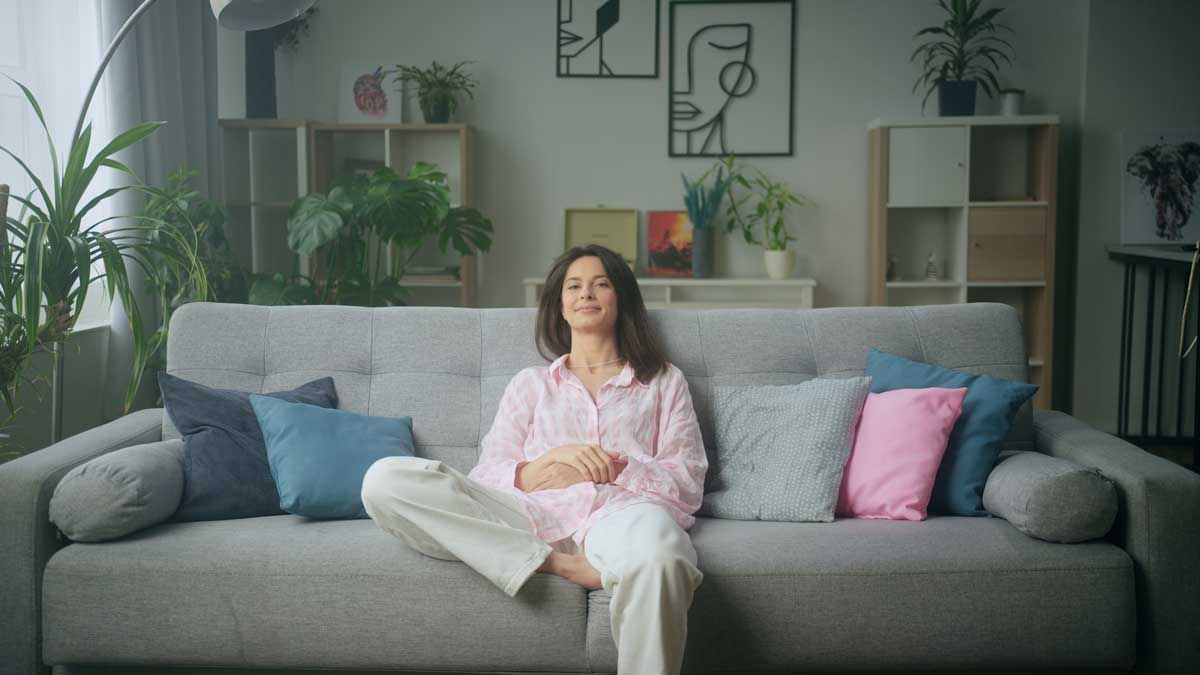 Ženina relaxace v útulném obývacím pokoji, který působí obydleně, barevně a přirozeně.