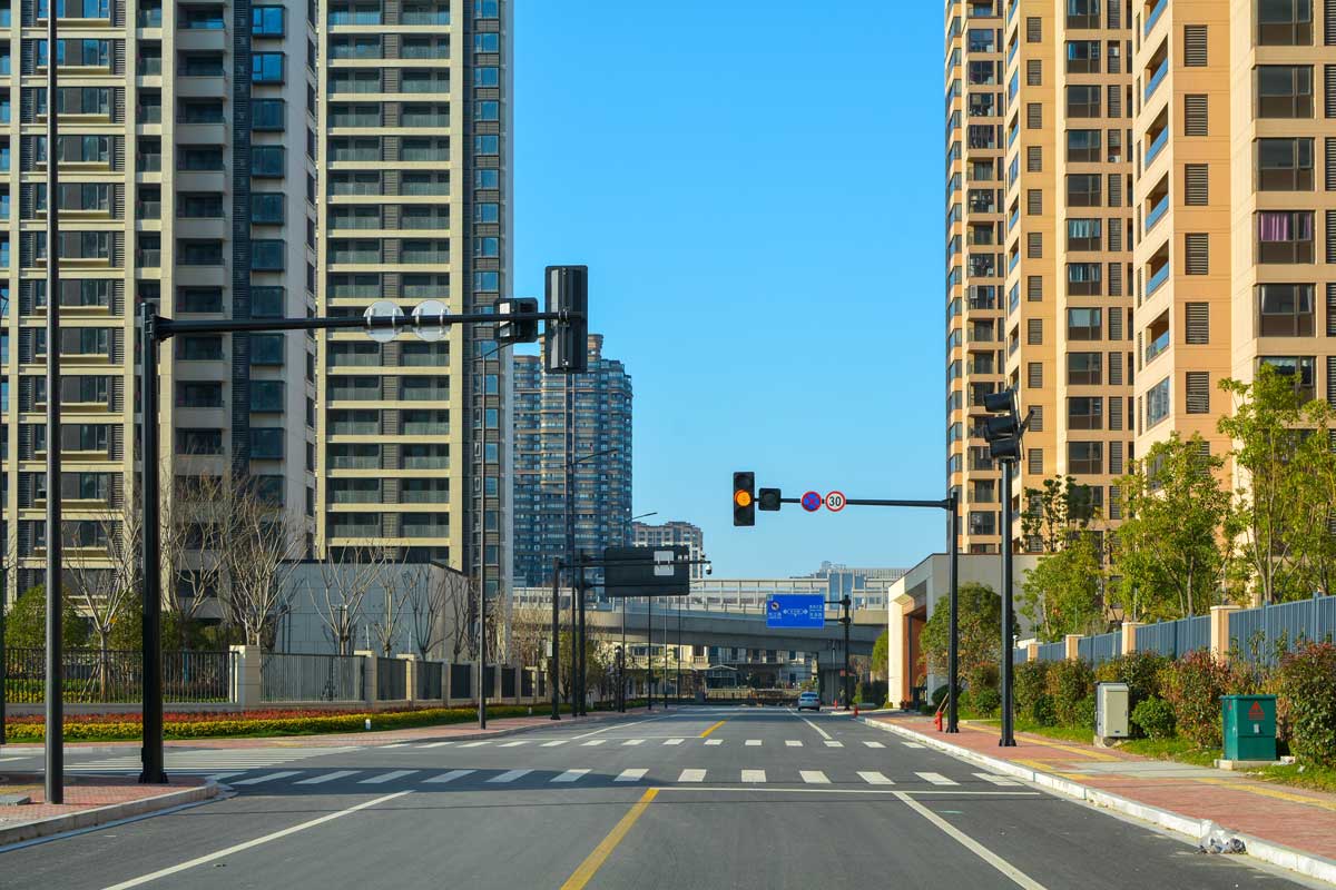 Prázdná široká ulice mezi novými obytnými věžovými domy v Jiaxingu.