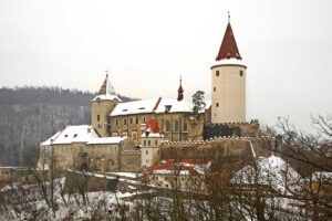 Hrad Křivoklát v zimě obklopený zasněženými lesy