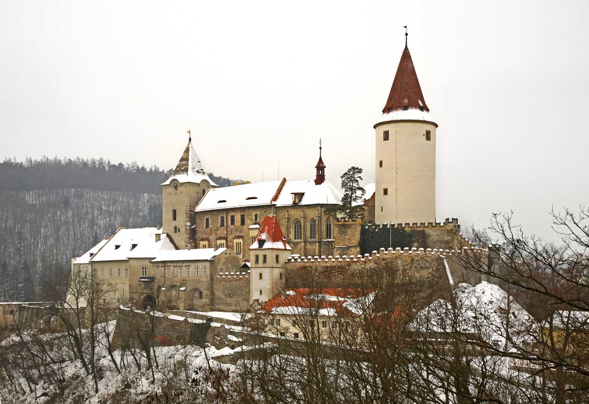 Hrad Křivoklát v zimě obklopený zasněženými lesy