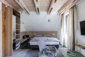 Ložnice v horské chatě s dřevěnými trámy a minimalistickým interiérem