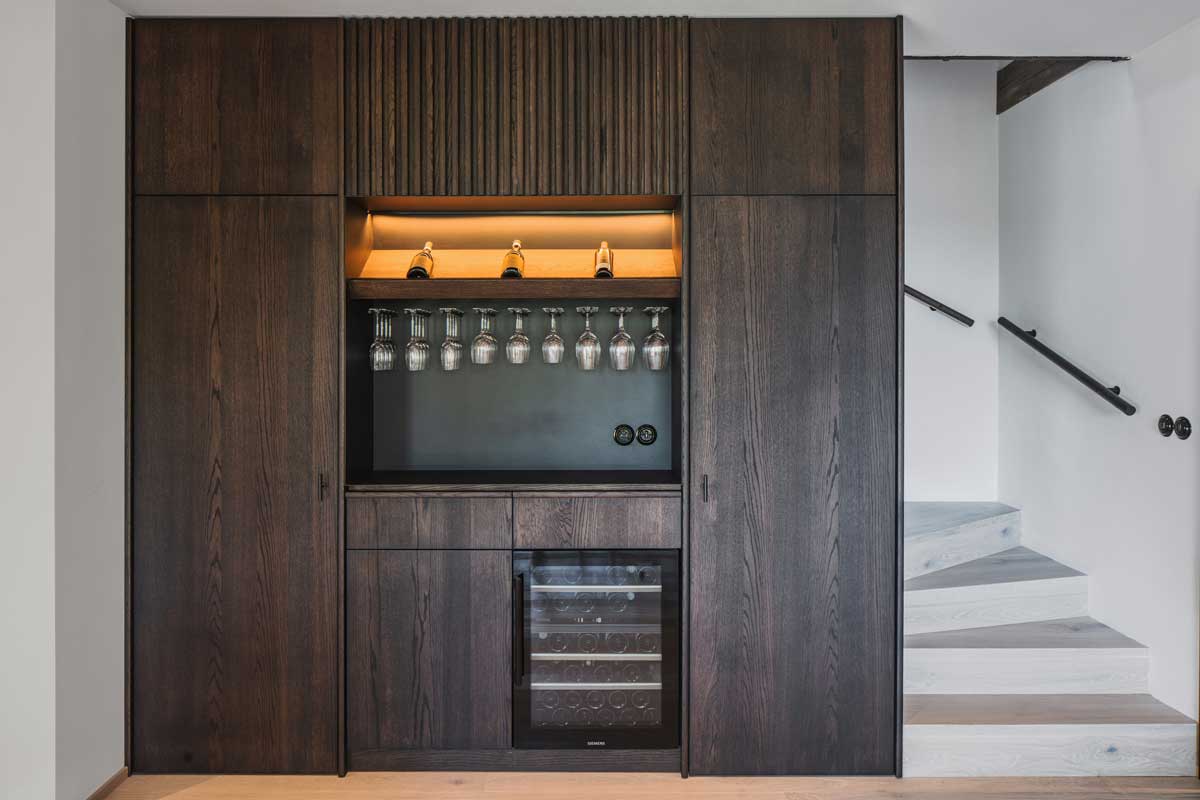Vestavěná vinotéka a bar obepínající schodiště v moderní horské chalupě