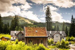 Moderní horská chata se zelenou střechou zasazená do horské krajiny