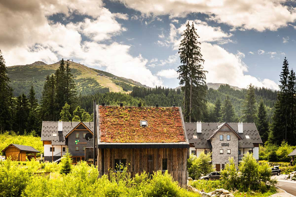 Moderní horská chata se zelenou střechou zasazená do horské krajiny