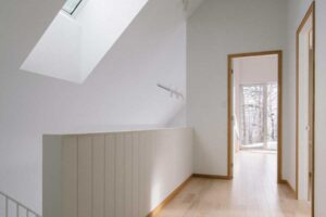 Světlá chodba dává vyniknout čistým liniím a zve pohledem ven do ticha zasněženého lesa.