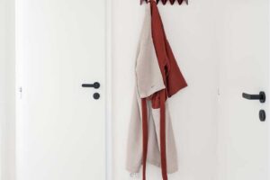 Světlá chodba s bílými dveřmi, minimalistickým věšákem a jemným terrazzo podkladem.