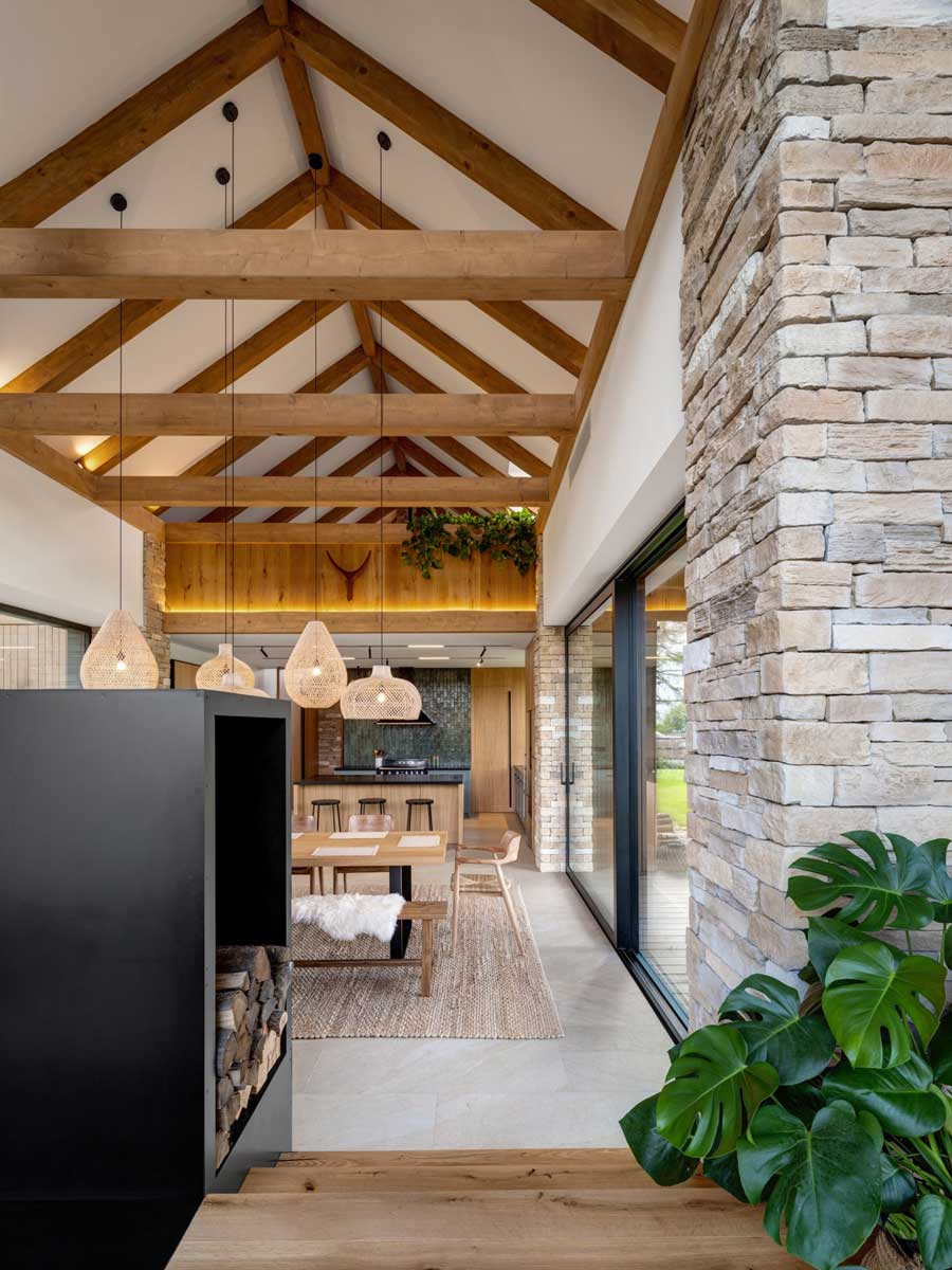 Propojení jídelny, obývacího pokoje a kuchyně v otevřeném prostoru s dřevěnými trámy a prosklením