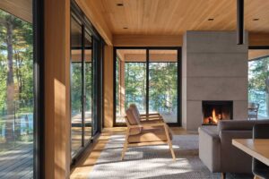 Obytný prostor s krbem uprostřed místnosti a prosklenými stěnami