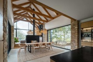 Jídelna moderní chaty s krbem, dřevěnými trámy a velkorysým výhledem do krajin