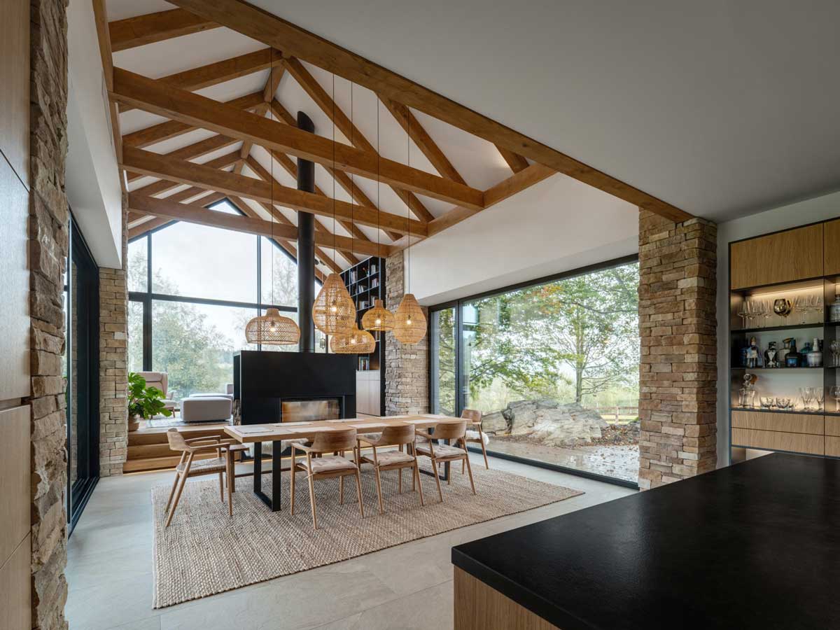 Jídelna moderní chaty s krbem, dřevěnými trámy a velkorysým výhledem do krajin